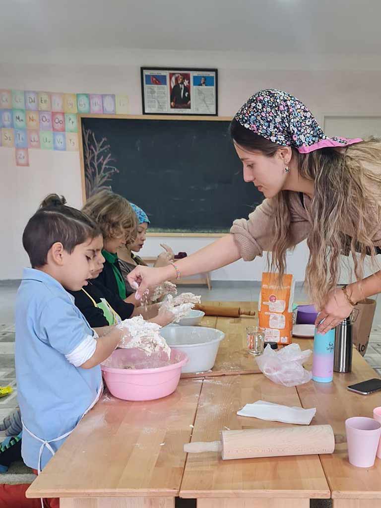 Öğrenciler bu derste hamur yoğuruyorlar. Bir sonraki derste, arkada görünen harf çalışmalarına devam edecekler. 2024.